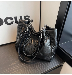 Close-up of black quilted nylon tote bag with silver chain strap and metal hardware