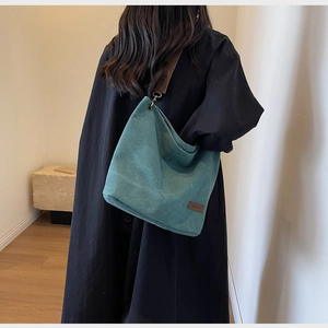 Detail of the large canvas bucket bag in teal with adjustable brown leather shoulder strap