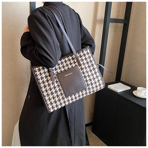 Detailed back view of a houndstooth tote bag worn on shoulder in a modern room