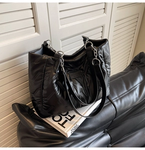 Detail of black quilted tote bag with V-stitch pattern and silver metal hardware