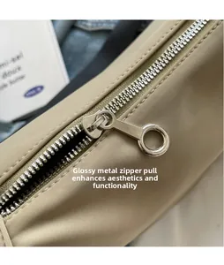 Close-up of smooth silver circular metal zipper on a durable khaki nylon crossbody bag