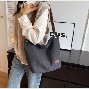 Close-up of charcoal canvas hobo bag with brown leather strap and fashion patch