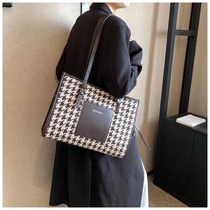 Detail of adjustable leather strap and houndstooth texture on large tote bag