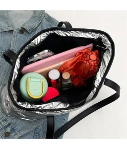Intérieur spacieux du sac cabas matelassé argenté contenant une tablette et des accessoires