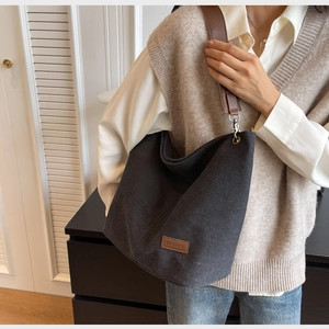 Detail of grey canvas bucket bag with brown leather FASHION patch and metal buckle strap
