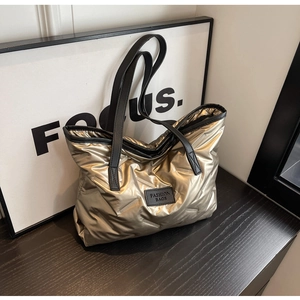 Détail du sac cabas matelassé doré avec lanières noires et étiquette en cuir