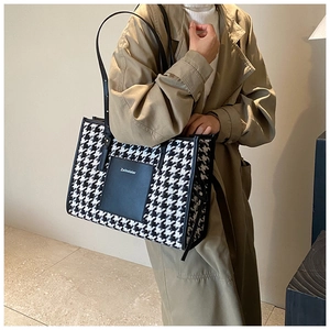 Detail of houndstooth tote bag with black leather pocket and shoulder strap on model