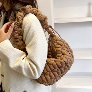 Brown quilted nylon hobo bag with pleated handle shown on model in white tweed coat