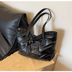 Gros plan du sac cabas matelassé noir brillant avec écusson logo de mode élégant