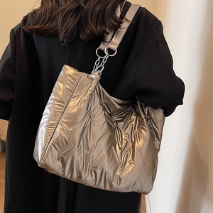 Metallic bronze quilted tote bag with chain strap shown on a black blazer for work