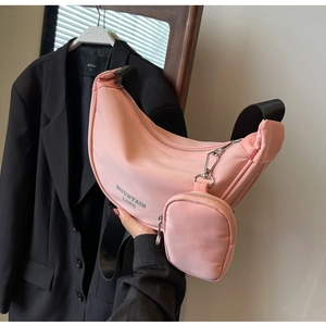 Detail of pink nylon crescent crossbody bag featuring adjustable black strap and coin pouch