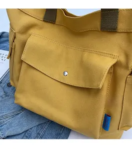 Close-up of yellow canvas tote bag showing thick texture and metal snap button pocket