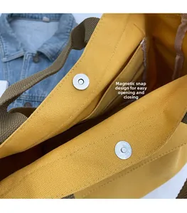 Detail of a yellow canvas tote bag showing its convenient magnetic snap closure