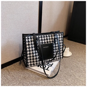 Macro detail of houndstooth fabric texture and leather handle on a large tote bag