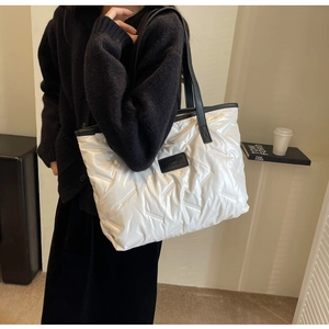 Detail of white quilted tote bag with black leather straps and fashion leather label