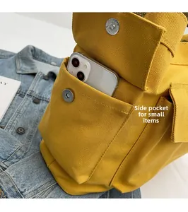 Detail of yellow canvas bag side pocket with magnetic flap and white smartphone storage
