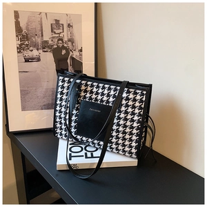 Detail of houndstooth tote bag with black leather trim and decorative tassel charm