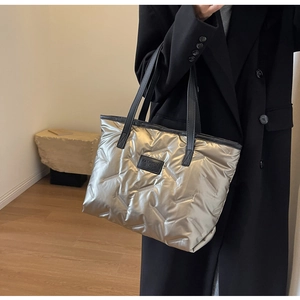 Fashionable silver quilted tote bag shown on person, featuring high-capacity metallic design