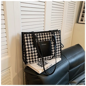 Detail of black and white houndstooth tote bag with leather pocket for office commuting