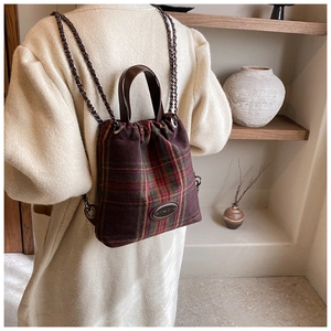 Detail eines Vintage-Karo-Rucksacks mit Ledergriff und Metallkettenriemen im Detail