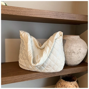 Detail shot of white quilted nylon shoulder bag with a soft padded finish and rhombus texture