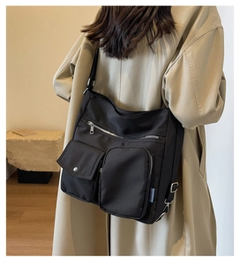 Detail of a black nylon utility bag featuring multiple pockets and metal hardware hooks