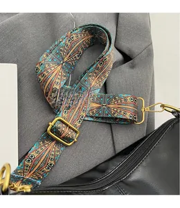 Detail view of ethnic style woven strap with blue orange patterns and golden metal hooks