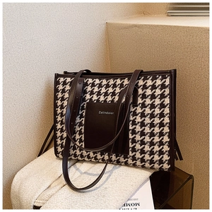 Detail of large houndstooth tote bag with brown leather trim and Zelindaier brand patch