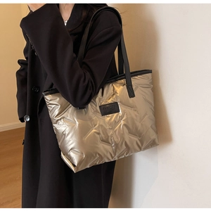 Close-up of champagne gold quilted tote bag with V-shaped stitching and fashion tag