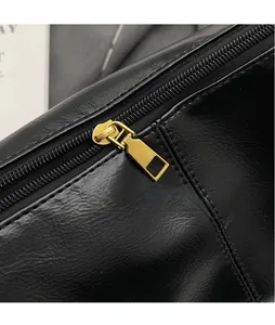 Close-up of golden zipper hardware on black pleated leather dumpling bag with oily texture