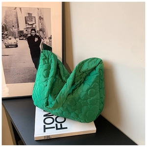 Detail of green quilted tote bag with floral stitching and padded nylon texture