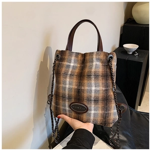 Detailansicht der braun karierten Wollhandtasche mit Ledergriff und Metallkettenriemen