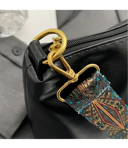 Close-up of golden hardware D-ring and colorful bohemian strap on black textured bag