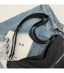 Detail of adjustable nylon shoulder strap with silver metal buckle on a black tote bag