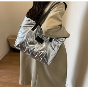 Detail of silver quilted tote bag showing high-gloss metallic finish and leather strap