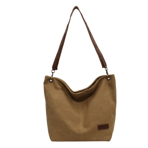 Brown canvas bucket shoulder bag with faux leather strap and minimalist fashion tag