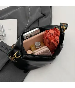Detail view of large black crossbody bag interior with colorful geometric wide strap