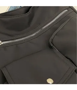 Detail of silver metal zipper and snap button pocket on lightweight black nylon bag