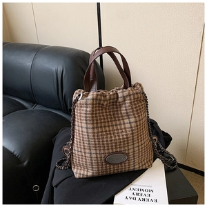 Detailansicht der braunen Tweed-Beuteltasche mit Ledergriff und Gliederkette aus Metall
