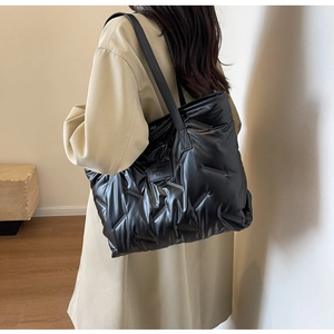 Close-up of black quilted puffer tote bag with Fashion Bags patch worn by a model