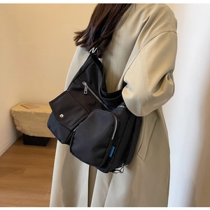 Detail der schwarzen Nylon-Umhängetasche mit funktionalen Zipp-Taschen und Silber-Dekor