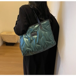Model wearing a glossy metallic green quilted tote bag with large capacity and straps