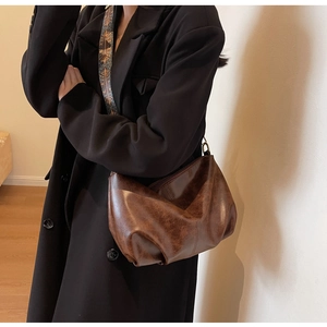Detail of vintage brown pleated bag with retro metal hardware and wide ethnic strap