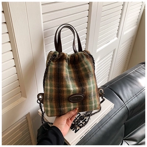 Detail der flauschigen Karo-Eimertasche mit Ledergriffen und Metallkettenriemen