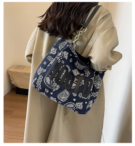 Detail of navy paisley canvas tote bag featuring HOOTO patch and chain strap worn by model