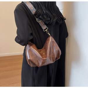 Detail of vintage brown leather dumpling bag with wide ethnic geometric shoulder strap