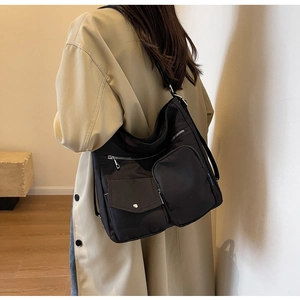 Details einer großen schwarzen Nylon-Hobo-Tasche mit Taschen und silbernen Beschlägen