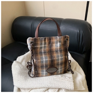 Detail der Vintage-Woll-Eimertasche mit braunen Ledergriffen und Metallkette im Karomuster