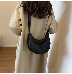 Detailed view of black nylon dumpling bag with adjustable wide strap shown on model