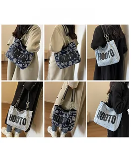 Detail of canvas tote bag featuring HOOTO lettering and metal chain leather straps